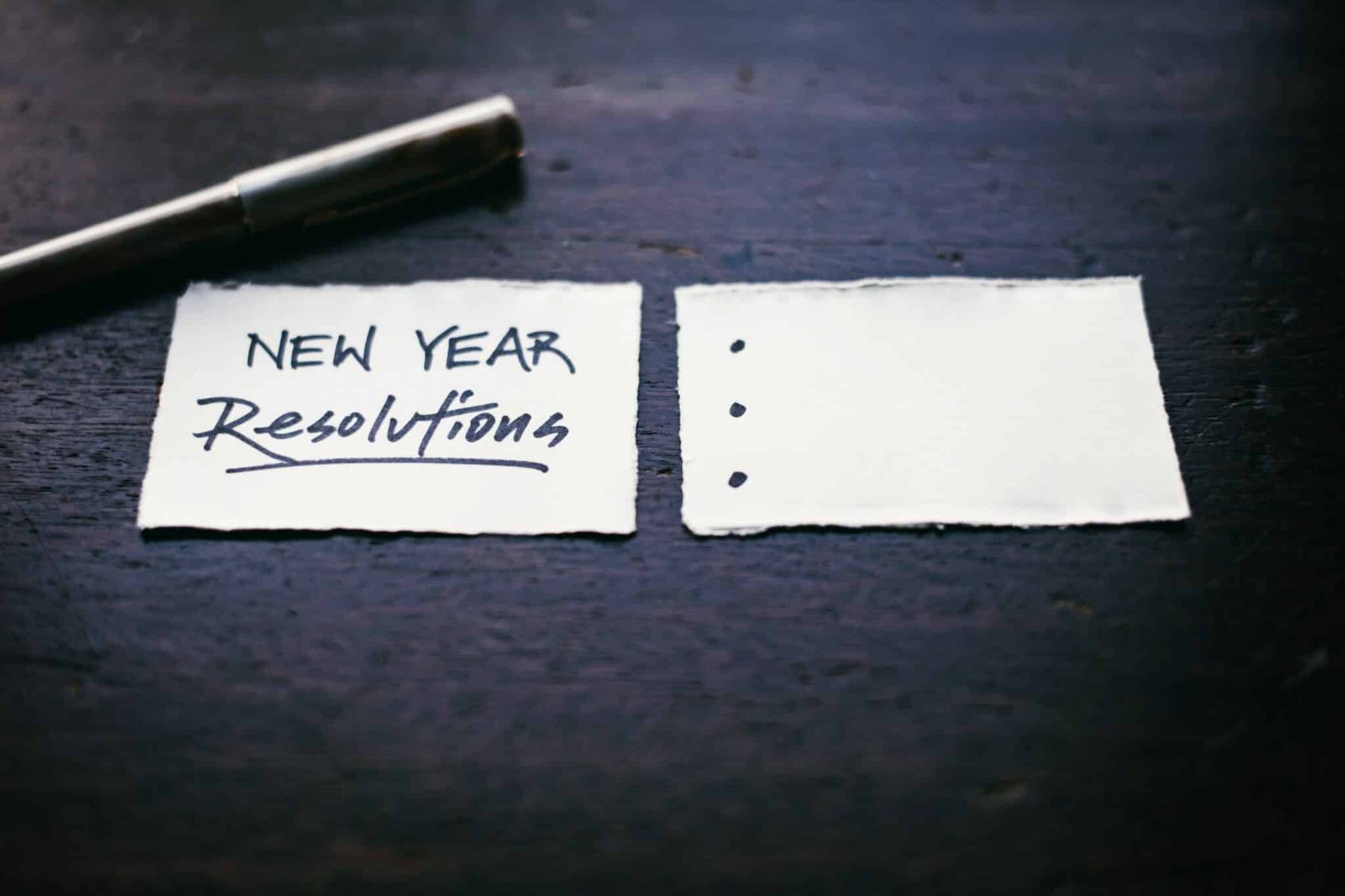 Two scraps of paper. The left one has "Fresh Year Resolutions" written, and the right one has three bullet points that are blank.