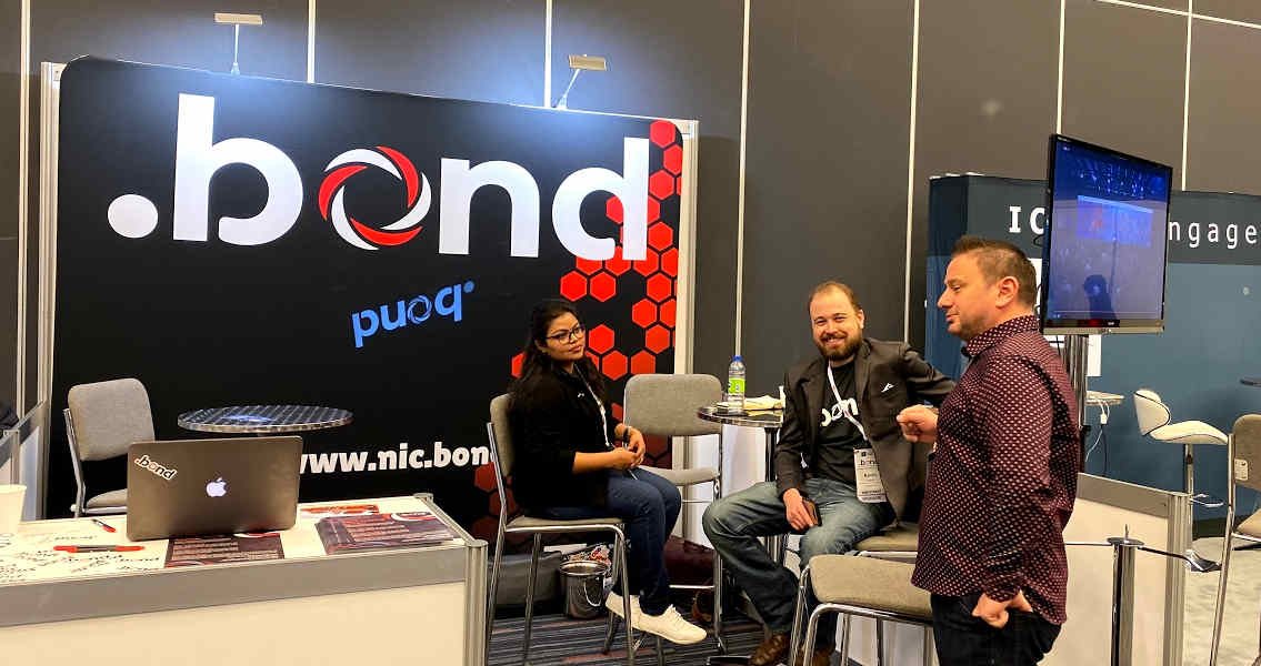 Picture of people at exhibition booth for .bond domain name