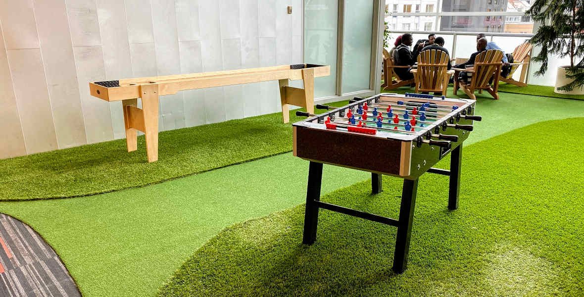 Picture of foosball table and shuffleboard table on green artificial grass
