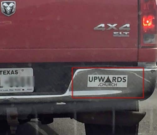 Red truck with a bumper sticker for upwards.church